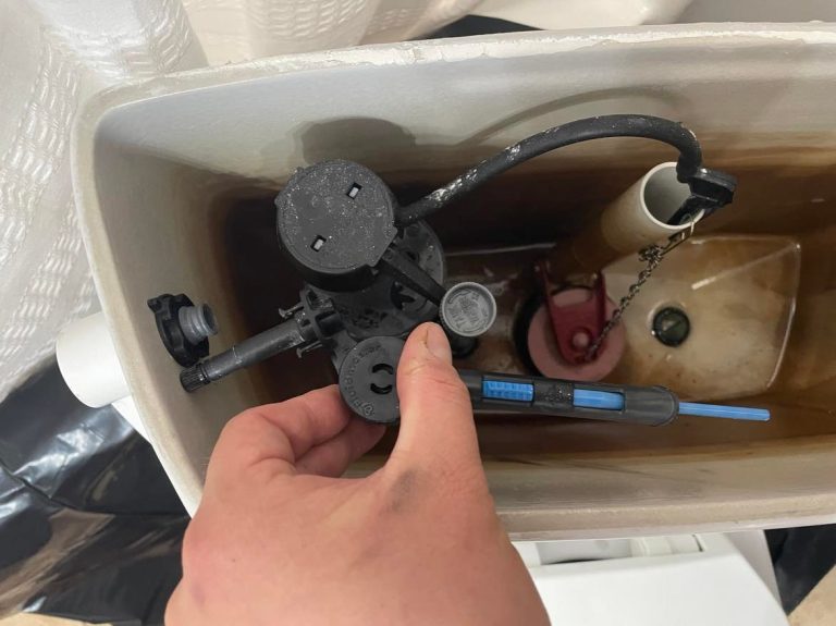 Toilet flush being adjusted inside the tank of an older toilet.